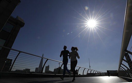 People run on Millenium Bridge over the River Thames in London, March 22, 2020. (AP Photo/Kirsty Wigglesworth)