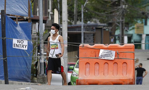 A man wearing a protective mask walks past an area cordoned off for an enhanced community quarantine aimed to prevent the spread of the new coronavirus in Manila, Philippines, Tuesday, March 24, 2020. For most people the new coronavirus causes only mild or moderate symptoms, but for some it can cause more severe illness. (AP Photo/Aaron Favila)