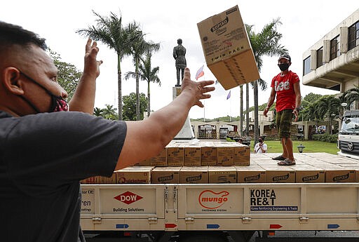 Volunteers and government workers unload boxes of canned food to be distributed to families following the enhanced community quarantine aimed to prevent the spread of the new coronavirus in Manila, Philippines on Tuesday, March 24, 2020. For most people the new coronavirus causes only mild or moderate symptoms, but for some it can cause more severe illness. (AP Photo/Aaron Favila)