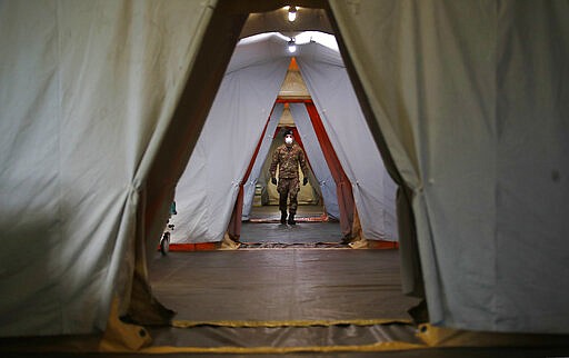 An Italian soldier walks inside the field hospital built in Crema, Italy, Tuesday, March 24, 2020. Cuba has sent a medical brigade to Italy to help treat coronavirus patients in the field hospital that was set up in Crema, one of Northern Italy's areas most hit by the virus. For most people, the new coronavirus causes only mild or moderate symptoms. For some it can cause more severe illness, especially in older adults and people with existing health problems. (AP Photo/Antonio Calanni)