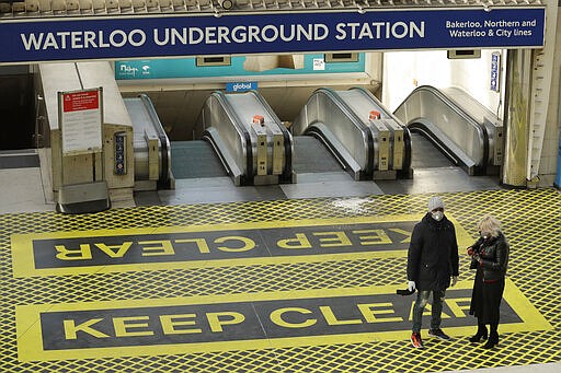 Two people waring masks stand at the top of a bank of escalators in London's Waterloo Station in London, Tuesday, March 24, 2020. Britain's Prime Minister Boris Johnson on Monday imposed its most draconian peacetime restrictions due to the spread of the coronavirus on businesses and gatherings, health workers begged for more gear, saying they felt like &quot;cannon fodder.&quot; For most people, the new coronavirus causes only mild or moderate symptoms. For some it can cause more severe illness. (AP Photo/Matt Dunham)