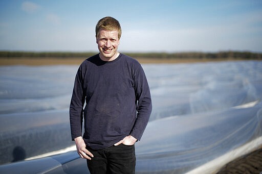 Farmer Henning Hoffheinz poses for a photo in front of one of his asparagus fields near Genthin, Germany, Wednesday, March 18, 2020. Last year, German farmers employed nearly 300,000 seasonal workers but as more and more European Union countries have restricted or stopped crossings of their usually near-invisible borders because of the coronavirus outbreak, Hoffheinz and others are left wondering how they will bring in their crops this year. (AP Photo/Markus Schreiber)