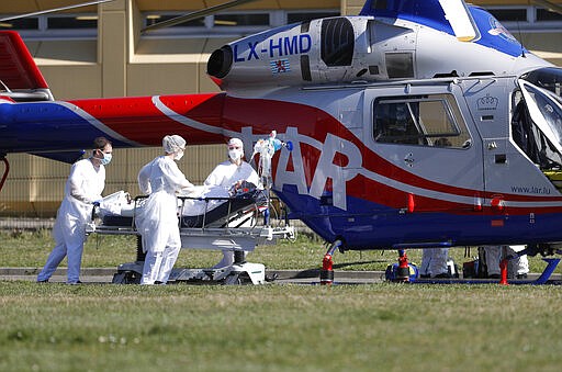 FILE - In this photo taken Monday March 23, 2020, a victim of the Covid-19 virus is evacuated from the Mulhouse civil hospital, eastern France. The Grand Est region is now the epicenter of the outbreak in France, which has buried the third most virus victims in Europe, after Italy and Spain. For most people, the new coronavirus causes only mild or moderate symptoms. For some it can cause more severe illness. (AP Photo/Jean-Francois Badias, File)