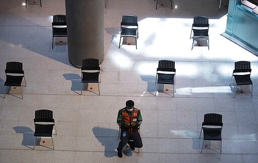 People practice social distancing as they sit on chairs spread apart in a waiting area for take-away food orders at a shopping mall in hopes of preventing the spread of the coronavirus in Bangkok, Thailand, Tuesday, March 24, 2020. (AP Photo/Sakchai Lalit)