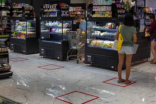 Customers stand in an area marked to prompt social distancing leading to cashers at a supermarket in Bangkok, Thailand, Tuesday, March 24, 2020. Most popular shopping malls remained shut in Bangkok, except supermarkets and pharmacies to combat the spread of new coronavirus. For most people, the new coronavirus causes only mild or moderate symptoms. For some, especially older adults it can cause more severe illness. (AP Photo/Gemunu Amarasinghe)