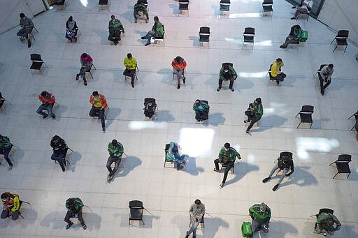 People practice social distancing as they sit on chairs spread apart in a waiting area for take-away food orders at a shopping mall in hopes of preventing the spread of the coronavirus in Bangkok, Thailand, Tuesday, March 24, 2020. (AP Photo/Sakchai Lalit)