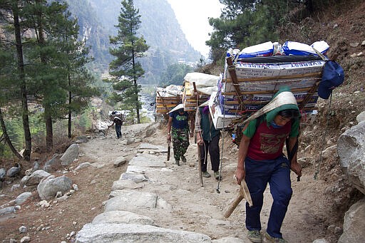 FILE - In this Tuesday, March 24, 2015, file photo, porters with supplies for trekkers head towards Namche, in Zamphute, a village in Nepal. The closure of Mount Everest will have significant financial ramifications for the local Sherpas, cooks, porters and other personnel who make their living during the short climbing window.  (AP Photo/Tashi Sherpa, file)