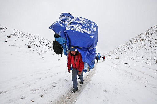 FILE - In this March 28, 2016, file photo, a porter walks with a massive load towards Everest Base camp near Lobuche, Nepal. The closure of Mount Everest due to the coronavirus will have significant financial ramifications for the local Sherpas, cooks, porters and other personnel who make their living during the short climbing window. There are thousands of people who depend on the money spent by climbers in Nepal. (AP Photo/Tashi Sherpa, file)