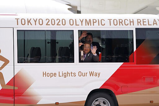 FILE - In this March 20, 2020, file photo, Japanese comedians Mikio Date, foreground, and Takeshi Tomizawa leave with the Olympic flame during the Flame Arrival Ceremony at Japan Air Self-Defense Force Matsushima Base in Higashimatsushima in Miyagi Prefecture, north of Tokyo. The Tokyo Olympic torch relay will start Thursday, March 26 as planned in northern Fukushima prefecture, but with no torch, no torchbearers, no public, and little ceremony to avoid spreading the coronavirus. (AP Photo/Eugene Hoshiko, File)