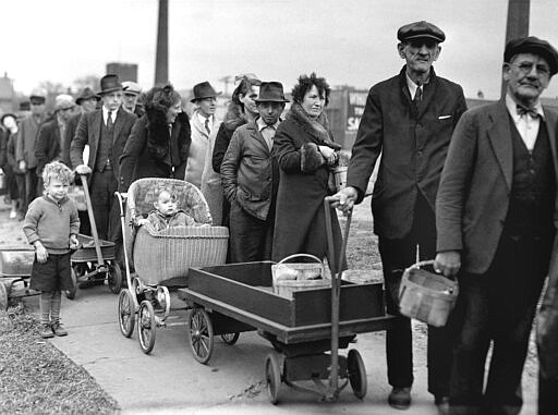 FILE - In this May 9, 1938 file photo, people stand in line for their portions of a federal surplus of potatoes and cabbages in Cleveland. Nearly a century later, the U.S. economy is all but shut down, and layoffs are soaring at small businesses and major industries. A devastating global recession looks inevitable. Deepening the threat, a global oil price war has erupted. Some economists foresee an economic downturn to rival the Depression. (AP Photo, file)