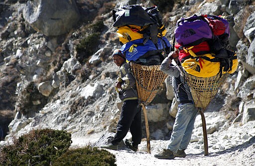 FILE - In this Sunday, Nov. 8, 2015, file photo, porters rest carrying the load of trekkers making their way back from Everest Base Camp, near Shomare, Nepal. The closure of Mount Everest will have significant financial ramifications for the local Sherpas, cooks, porters and other personnel who make their living during this short climbing window. (AP Photo/Tashi Sherpa, File)