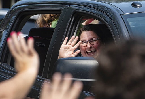 Andy Woods Elementary School teacher Rachel Diaz smiles and waves as she rides in a car passing by the houses of her students during a teachers parade in Tyler, Texas on Tuesday, March 24, 2020. Due to the spread of the corona virus, the Tyler Independent School District has transitioned to online learning, so the parade was a way for the students to see their teachers in person while staying at home. (Sarah A. Miller/Tyler Morning Telegraph via AP)