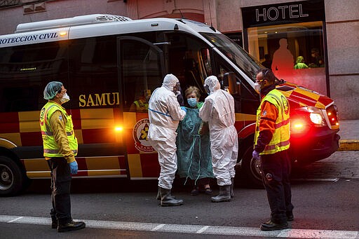 A patient, center, is transferred to a medicalised hotel during the COVID-19 outbreak in Madrid, Spain, Tuesday, March 24, 2020. For most people, the new coronavirus causes only mild or moderate symptoms. For some it can cause a more serious illness. (AP Photo/Bernat Armangue)