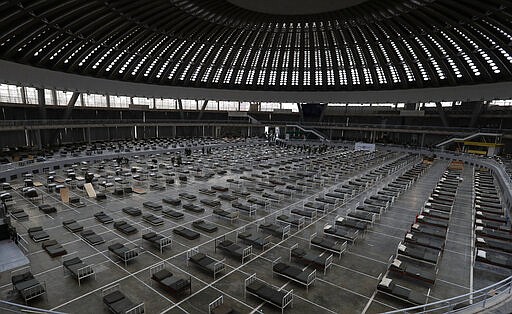 Serbian soldiers set up beds for treatment of possible COVID-19 infected patients inside of the Belgrade Fair, Serbia, Tuesday, March 24, 2020. For most people, the new coronavirus causes only mild or moderate symptoms. For some it can cause more severe illness. (AP Photo/Darko Vojinovic)