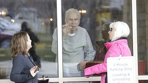 Kaye Knighton, 86, receives a visit from his daughter-law Darla Knighton, left, and Debbie Atkins, right, at the Creekside Senior Living Tuesday, March 24, 2020, in Bountiful, Utah. Window visits help seniors connect to families despite coronavirus restrictions. (AP Photo/Rick Bowmer)