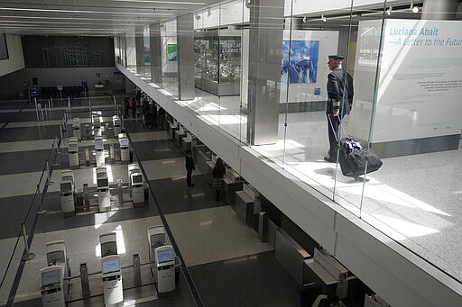 A pilot looks over sparse crowds at a check-in counter at the United terminal at Los Angeles International Airport, Tuesday, March 24, 2020, in Los Angeles. (AP Photo/Chris Carlson)