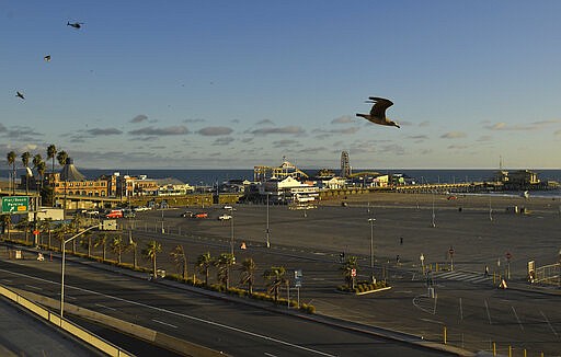 Light traffic and a mostly empty parking lot is seen along Pacific Coast Highway at the Santa Monica Pier, Monday, March 23, 2020, in Santa Monica, Calif. Officials are trying to dissuade people from using the beaches after California Gov. Gavin Newsom ordered the state's 40 million residents to stay at home indefinitely. His order restricts non-essential movements to control the spread of the coronavirus that threatens to overwhelm the state's medical system. (AP Photo/Mark J. Terrill)