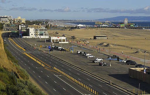 Light traffic and a mostly empty parking lot is seen along Pacific Coast Highway, Monday, March 23, 2020, in Santa Monica, Calif. 2020. Gov. Gavin Newsom said he would close parking lots at dozens of beaches and state parks to prevent the spread of coronavirus after large groups flocked to the coast and mountains to get outdoors on the first weekend since the state's stay-at-home order took effect. (AP Photo/Mark J. Terrill)