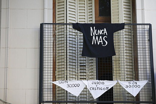 The Spanish messages &quot;They are 30,000,&quot; referring to the number of people who disappeared during the last dictatorship, &quot;Judgment and punishment,&quot; and &quot;Never again&quot; hang from a balcony on handkerchiefs and a T-shirt in Buenos Aires, Argentina, Tuesday, March 24, 2020. Today marks the anniversary of the military coup that led to the 1976-83 dictatorship, but as people are not allowed to march due to the government's lockdown to help contain the spread of the coronavirus, people are finding other ways to mark the day. (AP Photo/Natacha Pisarenko)