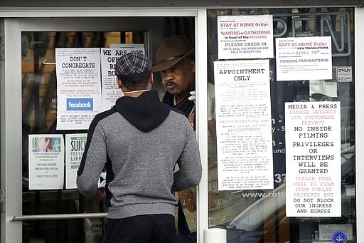 An employee answers questions at the entrance to a gun shop Tuesday, March 24, 2020, in Los Angeles. Los Angeles County Sheriff Alex Villanueva said he would like to see gun shops shut down. &quot;We will be closing them, they are not an essential function,&quot; Villanueva said. Adding guns to households where more people are at home during a crisis increases the risk that someone will be shot, he said. (AP Photo/Marcio Jose Sanchez)