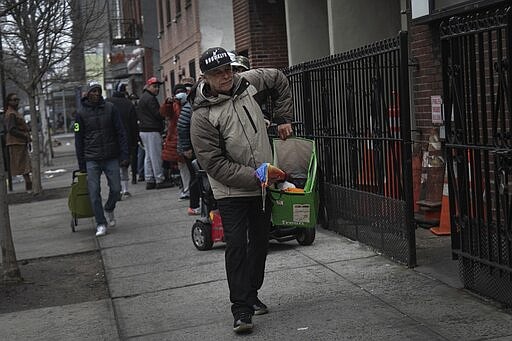 Jose Rosa, 63, moves forward in the queue where he waits to collect food donations from St. Stephen Outreach in the Brooklyn borough of New York, on Friday, March 20, 2020. Jose Rosa, 63, comes to the soup kitchen once a week. He lives in a homeless shelter, and says he doesn't get enough to eat there. (AP Photo/Wong Maye-E)