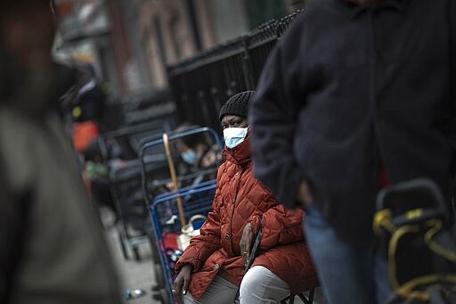 Mary Carter, 63, waits in a queue outside St. Stephen Outreach to collect food donations in the Brooklyn borough of New York, on Friday, March 20, 2020. For decades, American nonprofits have relied on a cadre of volunteers who quite suddenly aren't able to show up. With millions staying home during the pandemic, charities that help the country's neediest are facing even greater need. (AP Photo/Wong Maye-E)