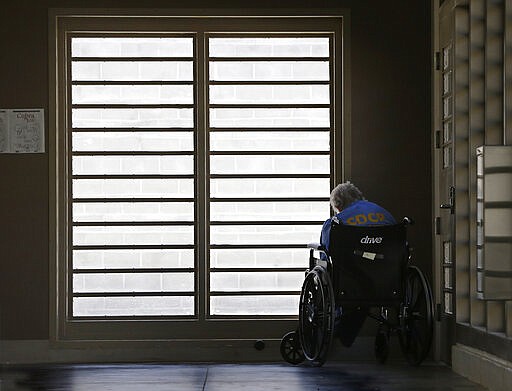 FILE - In this July 24, 2014, file photo, an inmate sits by a window at the mental health unit at the California Department of Corrections and Rehabilitation's Stockton Health Facility in Stockton, Calif. Public interest attorneys filed an emergency motion, Wednesday, March 25, 2020, asking federal judges to free thousands of infirm and lower-security California prison inmates to prevent a spread of the coronavirus. (AP Photo/Rich Pedroncelli, File)