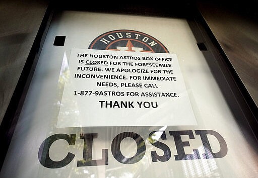 A sign is posted on a box office window at Minute Maid Park Wednesday, March 25, 2020 in Houston. The Houston Astros would have hosted the Los Angeles Angels in their season-opening baseball game Thursday. The start of the regular season is indefinitely on hold because of the coronavirus pandemic. (AP Photo/David J. Phillip)