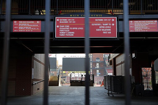 A concourse inside Busch Stadium, home of the St. Louis Cardinals baseball team, is seen through a locked gate Wednesday, March 25, 2020, in St. Louis. The start of the regular season, which was set to start on Thursday, is on hold indefinitely because of the coronavirus pandemic. (AP Photo/Jeff Roberson)