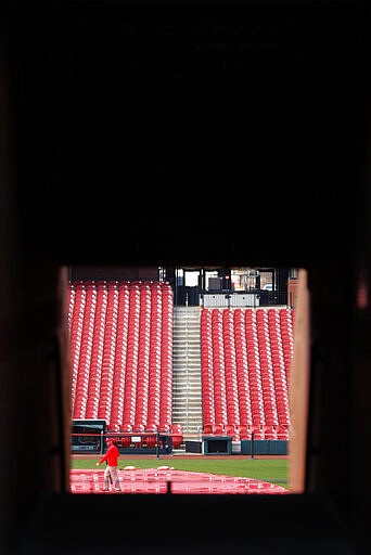 A grounds crew member walks on the field inside Busch Stadium, home of the St. Louis Cardinals baseball team, Wednesday, March 25, 2020, in St. Louis. The start of the regular season, which was set to start on Thursday, is on hold indefinitely because of the coronavirus pandemic. (AP Photo/Jeff Roberson)