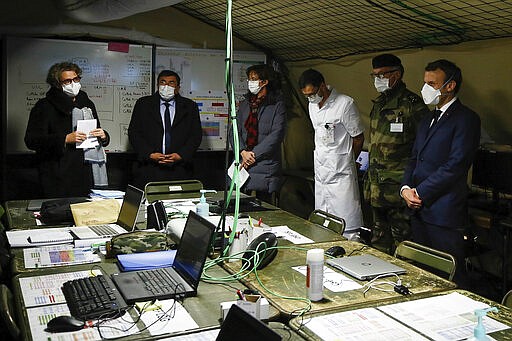 French President Emmanuel Macron, right, wears a face mask as he visits the military field hospital in Mulhouse, eastern France, Wednesday, March 25, 2020. French President Emmanuel Macron launched a special military operation Wednesday to help fight the new virus in one of the world's hardest-hit countries. The new coronavirus causes mild or moderate symptoms for most people, but for some, especially older adults and people with existing health problems, it can cause more severe illness or death. (Mathieu Cugnot/Pool via AP)