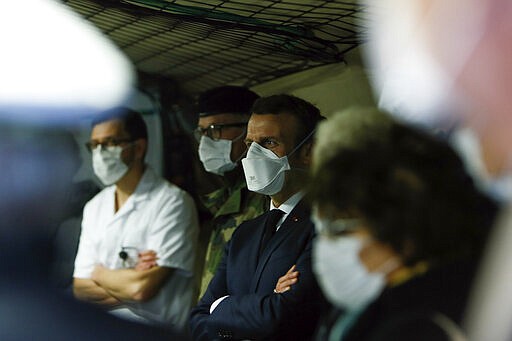 French President Emmanuel Macron, center, wears a face mask as he visits the military field hospital in Mulhouse, eastern France, Wednesday, March 25, 2020. French President Emmanuel Macron launched a special military operation Wednesday to help fight the new virus in one of the world's hardest-hit countries. The new coronavirus causes mild or moderate symptoms for most people, but for some, especially older adults and people with existing health problems, it can cause more severe illness or death. (Mathieu Cugnot/Pool via AP)