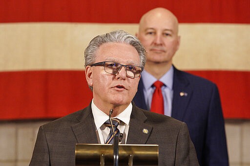 Nebraska Speaker of the Legislature, Jim Scheer of Norfolk, speaks during a press briefing with Neb. Gov. Pete Ricketts behind him, in Lincoln, Neb., Wednesday, March 25, 2020. Nebraska approved an $83.6 million emergency relief package Wednesday to help public health officials respond to new coronavirus as the number of cases continued to rise and Gov. Pete Ricketts expanded the list of counties where restaurants and bars will be forced to close their dining areas. (AP Photo/Nati Harnik)