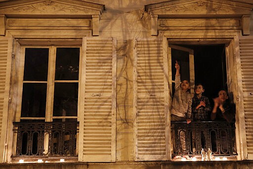 A woman and her children applaud after they set up candles on their balcony in Versailles, Wednesday, March 25, 2020. France's bishops called for Catholics and non-Catholics alike to take part in Wednesday's candle-lighting, in a shared &quot;prayer for the dead, the sick and their loved ones, for all the medical personnel and all those who make the life of our country possible.&quot; The new coronavirus causes mild or moderate symptoms for most people, but for some, especially older adults and people with existing health problems, it can cause more severe illness or death. (AP Photo/Christophe Ena)