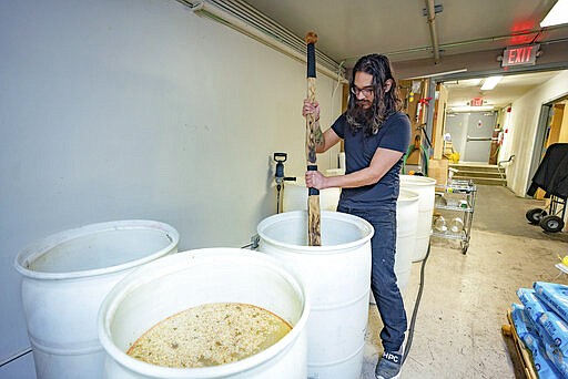 In this Tuesday, March 24, 2020 photo, Octavio Ramos, Silent Brigade Distillery bar manager, checks on a batch of mash at the distillery in downtown Paducah, Ky. Silent Brigade is making hand sanitizer and giving it to the public for free. Hand sanitizer has become a commodity in recent weeks due to the coronavirus pandemic. (Thomas Dean Stewart/The Paducah Sun via AP)