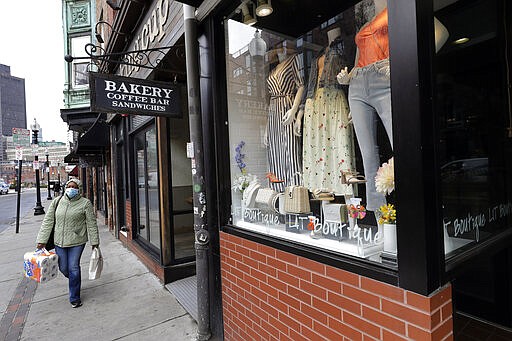 A pedestrian strolls past a fashionable boutique in the North End neighborhood of Boston, Tuesday, March 24, 2020. Mass. Gov. Charlie Baker ordered all nonessential businesses to close by Tuesday afternoon, and remain closed until at least April 7 in an effort to slow down the spread of the new coronavirus (AP Photo/Steven Senne)