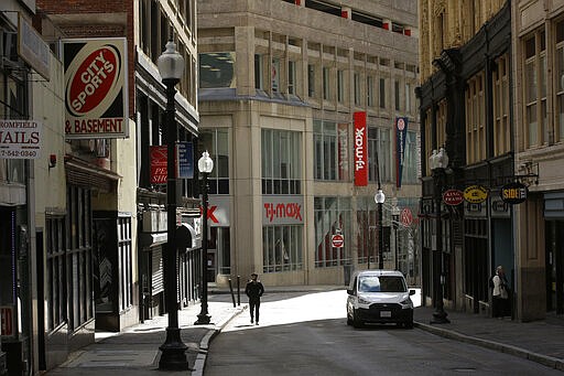 A passerby walks along a nearly empty street in the Downtown Crossing neighborhood of Boston, Tuesday, March 24, 2020. Many people are working from home in the state while many businesses have closed indefinitely out of concern about the spread of the coronavirus. (AP Photo/Steven Senne)