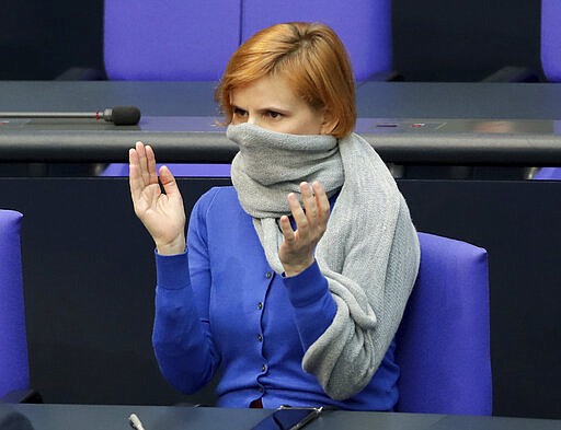 Due to the new coronavirus outbreak Katja Kipping, center, co-chairwoman of the German Left Party, wears a scraf as a face mask during a meeting of the German federal parliament, Bundestag, at the Reichstag building in Berlin, Germany, Wednesday, March 25, 2020. The new coronavirus causes mild or moderate symptoms for most people, but for some, especially older adults and people with existing health problems, it can cause more severe illness or death. (AP Photo/Michael Sohn)