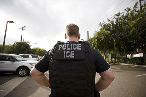 FILE - In this July 8, 2019, file photo, a U.S. Immigration and Customs Enforcement (ICE) officer looks on during an operation in Escondido, Calif.  Pressure is mounting on the Trump administration to release people from immigration detention facilities where at least one detainee has already tested positive for COVID-19.  (AP Photo/Gregory Bull, File)