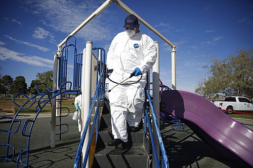 Workers clean and disinfect playground equipment due to the coronavirus outbreak at a park Wednesday, March 25, 2020, in Las Vegas. (AP Photo/John Locher)