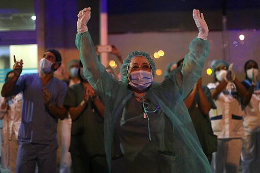 FILE, In this Saturday, March 21, 2020 file photo, health workers react as people applaud from their houses in support of the medical staff that are working on the COVID-19 virus outbreak at the Jimenez Diaz Foundation University hospital in Madrid, Spain. The coronavirus is winning a war of attrition waged against health care workers throughout the world but more so in Spain, where necessary equipment to shield them from contagion and enough testing kits for the new virus have been lacking for weeks. The new coronavirus causes mild or moderate symptoms for most people, but for some, especially older adults and people with existing health problems, it can cause more severe illness or death. (AP Photo/Manu Fernandez, File)