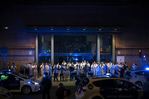 FILE, In this Monday, March 23, 2020 file photo, health workers gather outside the Hospital Clinic joining applause by police officers and residents in support of the medical staff that are working on the COVID-19 virus outbreak in Barcelona, Spain. The coronavirus is winning a war of attrition waged against health care workers throughout the world but more so in Spain, where necessary equipment to shield them from contagion and enough testing kits for the new virus have been lacking for weeks. The new coronavirus causes mild or moderate symptoms for most people, but for some, especially older adults and people with existing health problems, it can cause more severe illness or death. (AP Photo/Felipe Dana, File)