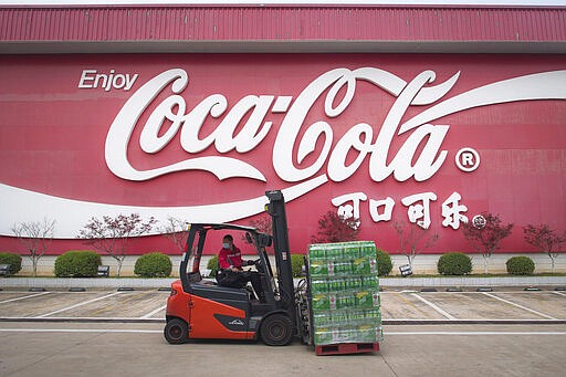 In this Tuesday, March 24, 2020, photo released by China's Xinhua News Agency, a worker wearing a face mask drives a forklift at a Swire Coca-Cola Beverages Hubei Limited plant in Wuhan in central China's Hubei Province. According to Chinese state media, the plant restarted some production lines on Monday. While many migrant workers across China remain trapped by travel bans due to the coronavirus, some industrial production has returned to action, including in the crucial auto manufacturing industry, which is largely based in Wuhan, and in businesses that provide critical links in global supply chains. The new coronavirus causes mild or moderate symptoms for most people, but for some, especially older adults and people with existing health problems, it can cause more severe illness or death. (Xiao Yijiu/Xinhua via AP)