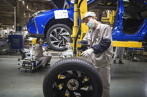 In this photo released by Xinhua News Agency, workers labor at an assembly line for Dongfeng Passenger Vehicle Company in Wuhan, in central China's Hubei Province, March 24, 2020. While many migrant workers across China remain trapped by travel bans due to the coronavirus, some industrial production has returned to action, including in the crucial auto manufacturing industry, which is largely based in Wuhan, and in businesses that provide critical links in global supply chains. (Xiao Yijiu/Xinhua via AP)