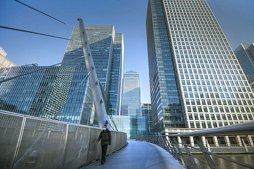 A man wearing a protective mask walks in Canary Wharf, during rush hour, in London, Wednesday March 25, 2020. For most people, the coronavirus causes mild or moderate symptoms, such as fever and cough that clear up in two to three weeks. (Victoria Jones/PA via AP)