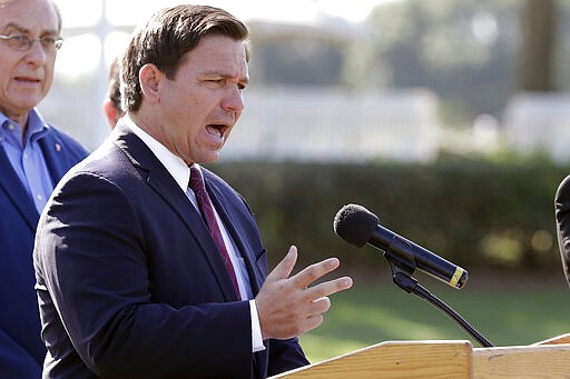 FILE- In this March 23, 2020 file photo, Florida Gov. Ron DeSantis delivers remarks during a press conference at a coronavirus mobile testing site in The Villages, Fla. The Villages, a retirement community, is one of the largest concentration of seniors in the U.S. Republican Gov. Ron DeSantis has been walking a tightrope for weeks during the coronavirus crisis, trying to protect both Floridians vulnerable to the virus and the cratering economy in a state of 21 million people.(AP Photo/John Raoux, File)