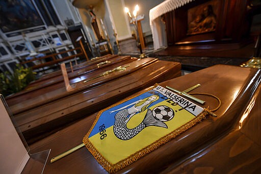 FILE - In this Saturday, March 21, 202 file photo, coffins, one of them with the pennant of the local soccer team, wait to be transported to cemetery, in the church of Serina, Seriana valley, where many Atalanta fans live, near Bergamo, Northern Italy. It was the biggest soccer game in Atalanta&#146;s history and a third of Bergamo&#146;s population made the short trip to Milan&#146;s famed San Siro Stadium to witness it. Nearly 2,500 fans of visiting Spanish club Valencia also traveled to the Champions League match. More than a month later, experts are pointing to the Feb. 19 game as one of the biggest reasons why Bergamo has become one of the epicenters of the coronavirus pandemic &#151; a &#147;biological bomb&#148; was the way one respiratory specialist put it &#151; and why 35% of Valencia&#146;s team became infected. The new coronavirus causes mild or moderate symptoms for most people, but for some, especially older adults and people with existing health problems, it can cause more severe illness or death. (Claudio Furlan/LaPresse via AP, File)