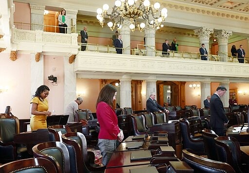 Representatives bow their heads as the Ohio House of Representatives was in session at the Statehouse in Columbus, Ohio, Wednesday, March 25, 2020. Representatives took precautions against coronavirus including spacing themselves throughout the chambers and gallery. (Barbara J. Perenic/The Columbus Dispatch via AP)