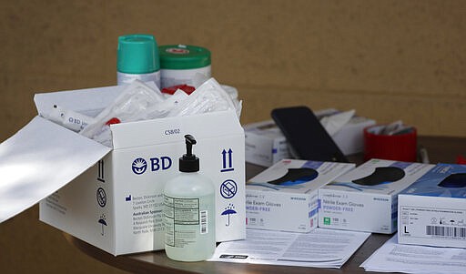 Boxes of gloves and syringes are seen on a table in a drive-thru site to test for the new coronavirus Wednesday, March 25, 2020, in at Stride Community Health Aurora, Colo. The new coronavirus causes mild or moderate symptoms for most people, but for some, especially older adults and people with existing health problems, it can cause more severe illness or death. (AP Photo/David Zalubowski)