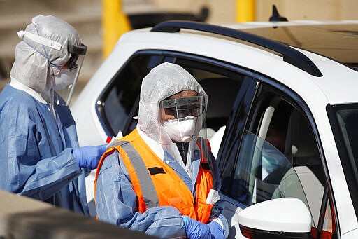 Medical technicians confer with individuals after administering a test for the new coronavirus Wednesday, March 25, 2020, at a drive-thru site at Stride Community Health in Aurora, Colo. The new coronavirus causes mild or moderate symptoms for most people, but for some, especially older adults and people with existing health problems, it can cause more severe illness or death. (AP Photo/David Zalubowski)